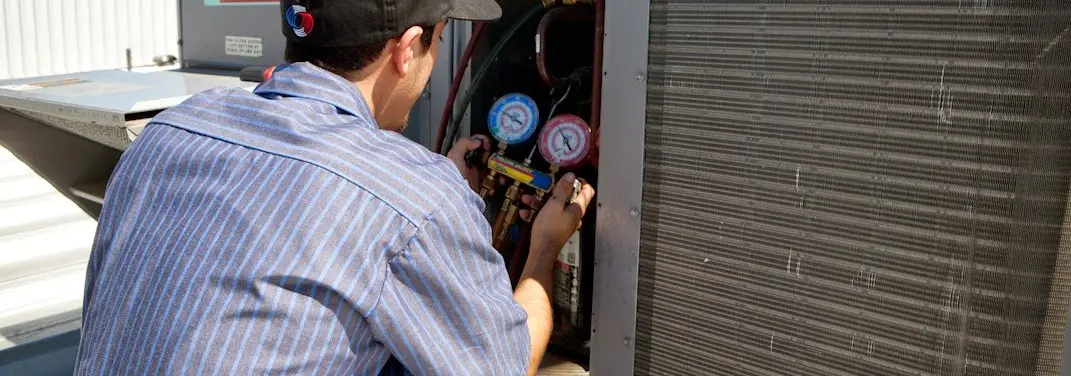 HVAC technician servicing a condenser unit in Merriam